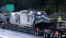 The engine from an Amtrak train that crashed onto Interstate 5 two days earlier is transported away from the scene, Dec. 20, 2017, in DuPont, Washington.