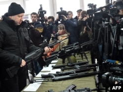 Ukraine -- Secretary of Ukrainian Security and Defennce Council Oleksandr Turchynov (L) examines a machine-gun during a presentation of new small arms, designed and made in Ukraine, at a shooting range near the village of Novi Petrivtsi, near Kyiv, Novemb