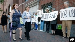 Boston Marathon bombing victim Erika Brannock, foreground left, and her mother, Carol Downing, foreground right, walk past demonstrators outside federal court in Boston, June 24, 2015.