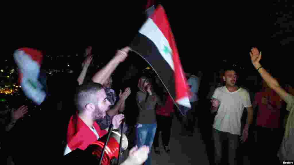 Pro-Assad demonstrators wave flags and shout slogans at Mount Qasioun, Damascus, Sept. 1, 2013. 