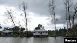 Small houses are seen by the bank of a river amidst polluted waterways in Gbaramatu kingdom, in Delta State, Nigeria, June 18, 2017.