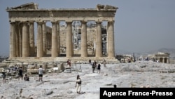 FILE - Tourists visit the Ancient Acropolis archeological site in Athens on July 1, 2021.