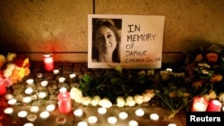 FILE - Candles burn to commemorate slain investigative journalist Daphne Caruana Galizia in Berlin, Oct. 20, 2017.