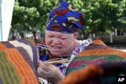 FILE - Tanzanian Albino, Muadhani Ramadhani, weaves an Africa tradition carpet (Mat) at Mnazi Mmoja grounds in Dares Salaam, May 4, 2007, as part of celebrations to mark World Albino Day. They appealed to the government and public at large that they disse