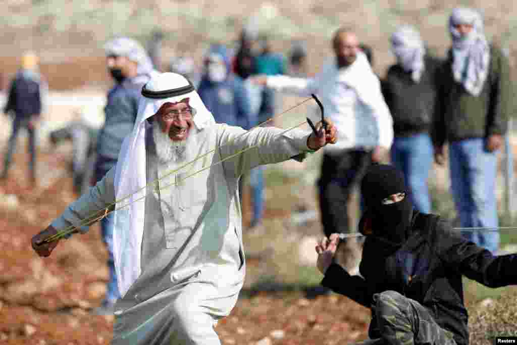 A Palestinian demonstrator uses a sling shot to hurl stones towards Israeli troops during a protest against Israeli settlements, in Deir Jarir in the Israeli-occupied West Bank.