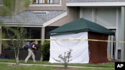 An FBI investigator walks to the apartment where a man was shot by an FBI agent, Wednesday, May 22, 2013, in Orlando, Fla.