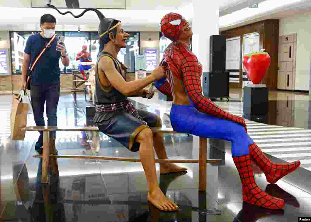 A man wearing a protective face mask takes a photo of an art exhibition at a shopping mall, amid the coronavirus disease (COVID-19) outbreak in Jakarta, Indonesia.