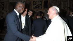 In this photo provided by the Vatican newspaper L'Osservatore Romano, Pope Francis greets Italy forward Mario Balotelli during a private audience at the Vatican, Aug. 13, 2013. 