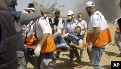 Palestinian medics evacuate a wounded photographer during a protest at the Gaza Strip's border with Israel, May 11, 2018.