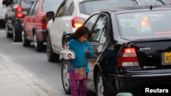 FILE - A girl sells candies along a street in the Miraflores district in Lima, Aug. 8, 2014. 