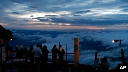 Para pendaki melihat pemandangan matahari terbit dari Gunung Fuji di kota Fujiyoshida, prefektur Yamanashi.
