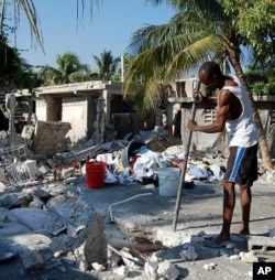 A man in Carrefour, Haiti, near the quake's epicenter, attempts to dig out whatever possessions he can salvage from his destroyed home, 25 Jan 2010