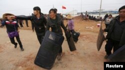 Villagers carry police shields taken from police injured during clashes at Fuyou village in Jinning county, Kunming, Yunnan province, Oct. 15, 2014. 