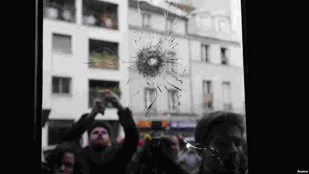 Journalists work outside a restaurant where bullet impacts are seen the day after a series of deadly attacks in Paris, France, Nov. 14, 2015. 