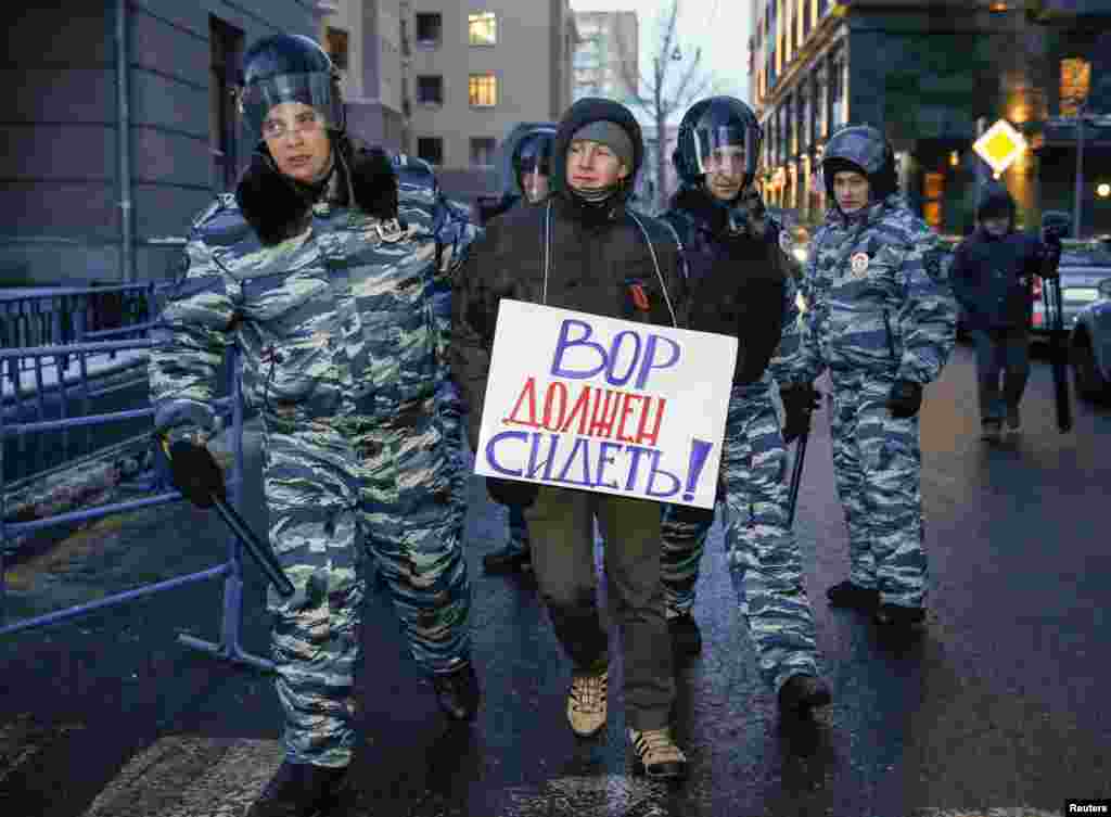 Policemen detain a supporter of opposition leader and anti-corruption blogger Alexei Navalny near a court building during his hearing in Moscow, Dec. 30, 2014.