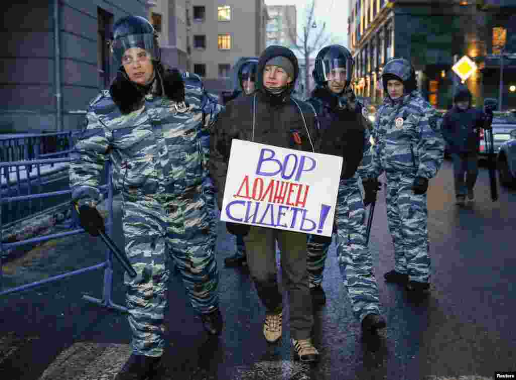 Policemen detain a supporter of opposition leader and anti-corruption blogger Alexei Navalny near a court building during his hearing in Moscow, Dec. 30, 2014.