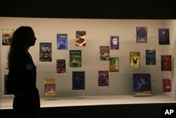 A member of British Library staff poses for a picture with Harry Potter books published in several languages at the "Harry Potter - A History of Magic" exhibition at the British Library, in London, Wednesday Oct. 18, 2017.