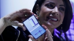 A woman holds a Samsung Galaxy Z Flip Phone displayed at the Unpacked 2020 event in San Francisco, Tuesday, Feb. 11, 2020. (AP Photo/Jeff Chiu)