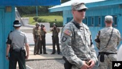 Shimoliy Koreya harbiylari chegarada turgan Janubiy Koreya askari (chapda) va Amerika harbiylarini kuzatmoqda. 27-iyul, 2014