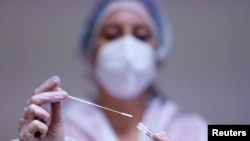 Un trabajador médico sostiene un tubo de ensayo después de administrar un hisopo nasal a un paciente con enfermedad por coronavirus (COVID-19). [Foto de archivo]