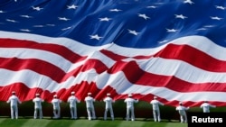 U.S. sailors unravel a huge American flag across the field during opening day ceremonies before the San Diego Padres host the Los Angeles Dodgers in their MLB National League baseball game in San Diego, California, April 9, 2013. 