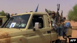 FILE -- Members of an armed group sit in a vehicle in Kidal, Mali, July 13, 2016. Clashes have been reported in the restive northern city between pro-government and former rebel groups, both based there since February. 