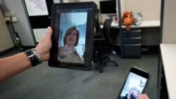 In this Friday, Aug. 13, 2021, photo Sheriff's Police Sgt. Bonnie Busching tests a video meeting from her personal electronic device with another person in the agency at the Cook County Sheriff's Office in Chicago. (AP Photo/Nam Y. Huh)