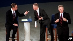 This October 15, 1992 photo shows then President George H. W. Bush, talking with independent candidate Ross Perot as Democratic candidate Bill Clinton stands aside at the end of their second presidential debate in Richmond, Virginia.