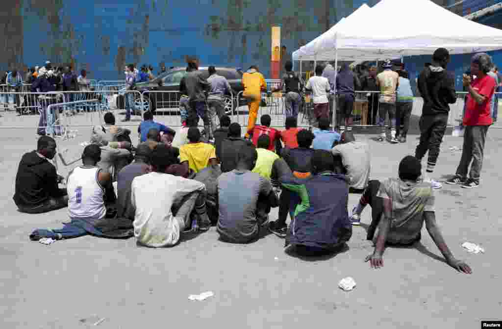 Groups of migrants wait after disembarking from a merchant ship at the Sicilian harbor of Catania, southern Italy, May 5, 2015.&nbsp;