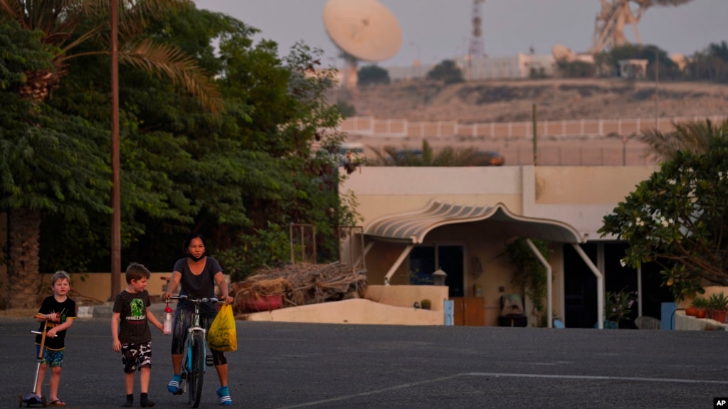 With a satellite station of a local telecommunication company behind them, 5-year-old Ryan Dickinson, left, 7-year-old Elliot Dickinson and housekeeper Jenny Ambas walk down a quiet street in Jebel Ali Village in Dubai, United Arab Emirates, Nov. 2, 2021.
(AP Photo/Jon Gambrell)