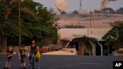 With a satellite station of a local telecommunication company behind them, 5-year-old Ryan Dickinson, left, 7-year-old Elliot Dickinson and housekeeper Jenny Ambas walk down a quiet street in Jebel Ali Village in Dubai, United Arab Emirates, Nov. 2, 2021.
(AP Photo/Jon Gambrell)