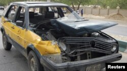 A car damaged by a bomb blast is seen in front of police headquarters in Nigeria's northeastern city of Maiduguri June 8, 2012.