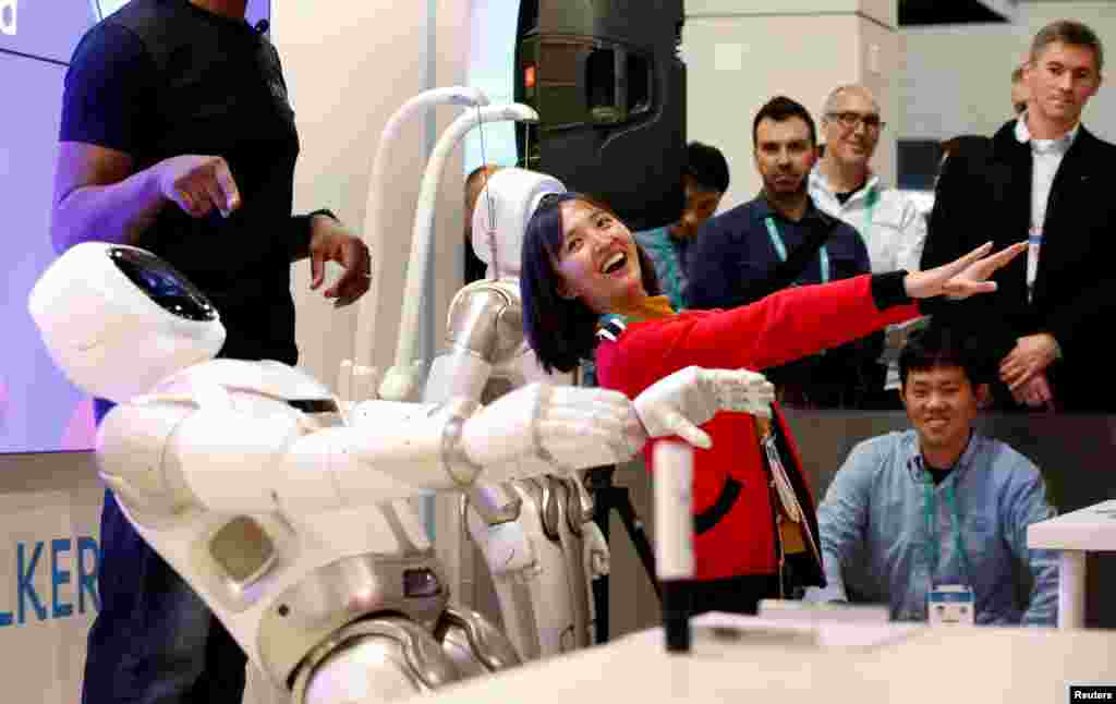 Tanli Yang, a journalist with China Global Television Network, performs yoga poses with Walker, an intelligent humanoid service robot, at the UB Tech booth during the 2020 CES in Las Vegas, Nevada, Jan. 8, 2020.