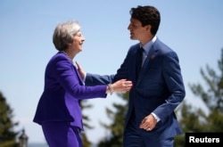Britain's Prime Minister Theresa May is greeted by Canada's Prime Minister Justin Trudeau as she arrives at the G7 Summit in Charlevoix, Quebec, Canada, June 8, 2018.