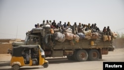 Les migrants assis sur leurs effets, voyagent au-dessus d’un camion qui traverse une route poussiéreuse dans la ville désertique d'Agadez, au Niger, en direction de la Libye, 25 mai 2015.