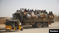 FILE - Migrants sit on their belongings in the back of a truck as it is driven through a dusty road in the desert town of Agadez, Niger, headed for Libya, May 25, 2015. 