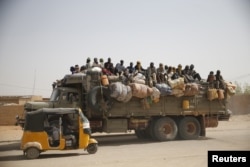 FILE - Migrants sit on their belongings in the back of a truck as it is driven through a dusty road in the desert town of Agadez, Niger, headed for Libya, May 25, 2015.