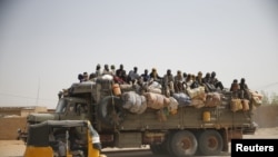 FILE - Migrants sit on their belongings in the back of a truck as it is driven through a dusty road in the desert town of Agadez, Niger, headed for Libya, May 25, 2015. 