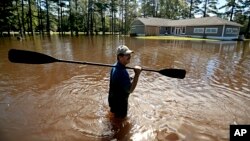 The home of Kenny Babb is surrounded by water as he retrieves a paddle that floated away while the Little River continues to rise in the aftermath of Hurricane Florence in Linden, N.C., Sept. 18, 2018. 