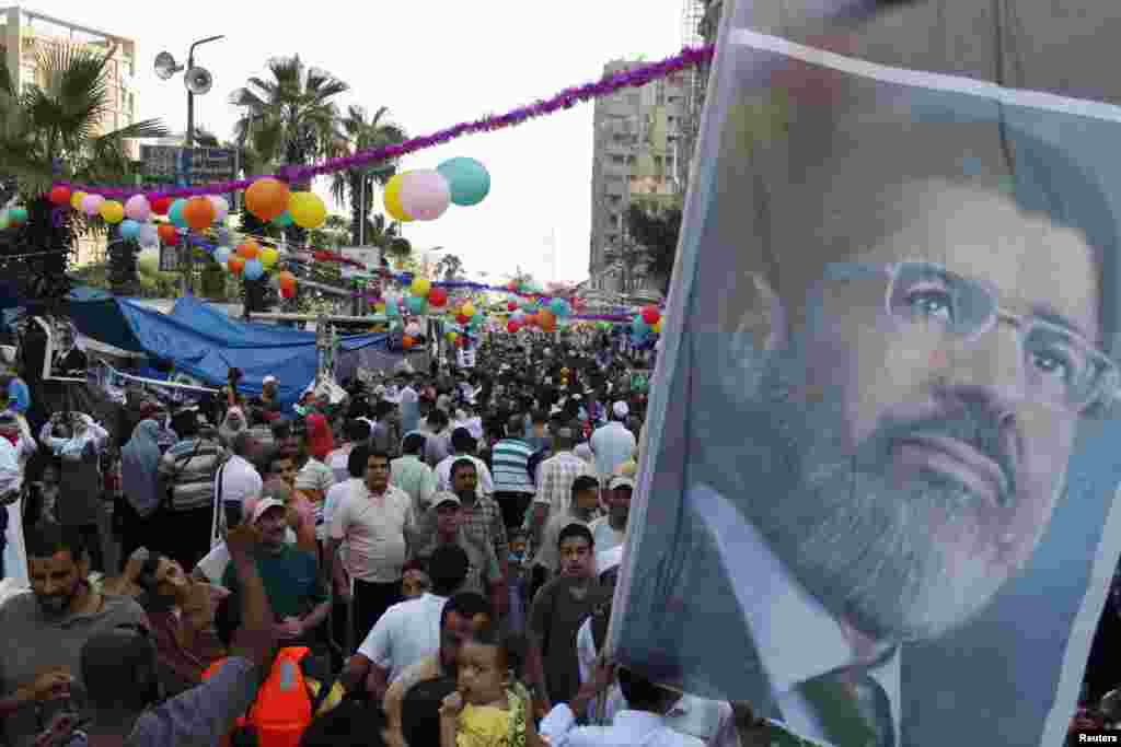 Members of the Muslim Brotherhood and supporters of deposed Egyptian President Mohamed Morsi hold a giant poster of him on the first day of the Eid al-Fitr, Cairo, August 8, 2013.