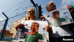 FILE - Demonstrators hold banners with the picture of Erol Onderoglu, local representative of Reporters Without Borders, during a protest against the arrest of three prominent activists for press freedom, in front of Metris prison in Istanbul, Turkey, June 24, 2016.