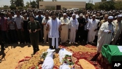 In this photo taken on a government-organized tour, Khaled, center, and Mohammed, center left, sons of Khoweildi al-Hamidi, a close associate of Moammar Gadhafi, left, pray among others next to bodies of two children during a funeral in the city of Surman