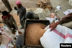 Men work in cleaning and arranging wheat for storage in Ras al-Ain, Syria, Sept. 16, 2016.