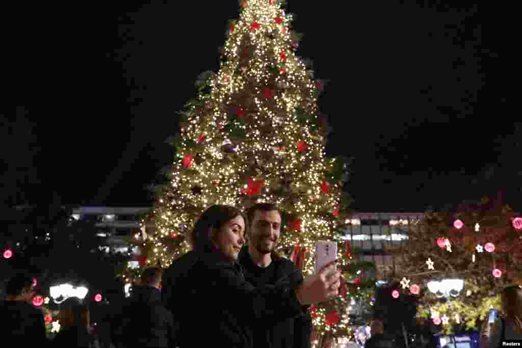 Una pareja se toma una selfie frente a un árbol de Navidad en la plaza Syntagma en Atenas, Grecia.