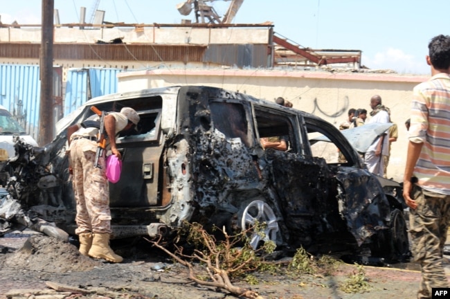 Pasukan keamanan Yaman dan tim penyelamat berkumpul di sekitar bangkai mobil yang terbakar menyusul ledakan yang melanda kota pelabuhan selatan Yaman, Aden, pada 10 Oktober 2021. (Foto: AFP)