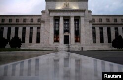 FILE - The facade of the U.S. Federal Reserve building is reflected on wet marble during the early morning hours in Washington.