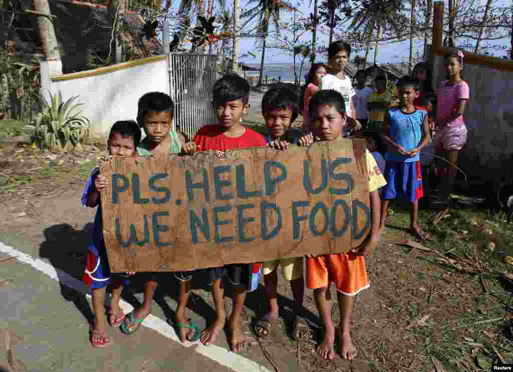 Typhoon victims display a placard asking for food from motorists by the side of a road in Dolores, Samar in central Philippines, Dec. 8, 2014.