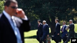 FILE - Members of President Donald Trump's administration walk past a Secret Service agent as they follow Trump to the Marine One helicopter on the South Lawn of the White House in Washington, Aug. 4, 2017. After Trump's controversial remarks on the violence in Charlottesville there is rising speculation that some top officials may be looking for way out.