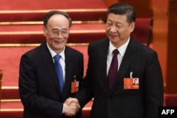 当选连任的中国国家主席习近平在中国第十三届全国人大全体会议上和当选中国国家副主席的王岐山握手（2018年3月17日）。