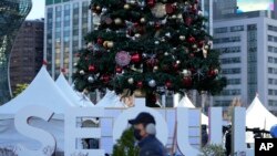 Seorang pria mengenakan masker, berjalan di depan dekorasi Natal dan pajangan logo ibu kota Korea Selatan Seoul di Seoul, Korea Selatan, Rabu, 1 Desember 2021. Lonjakan harian infeksi virus corona di Korea Selatan melebihi 5.000 untuk pertama kalinya sejak awal pandemi.